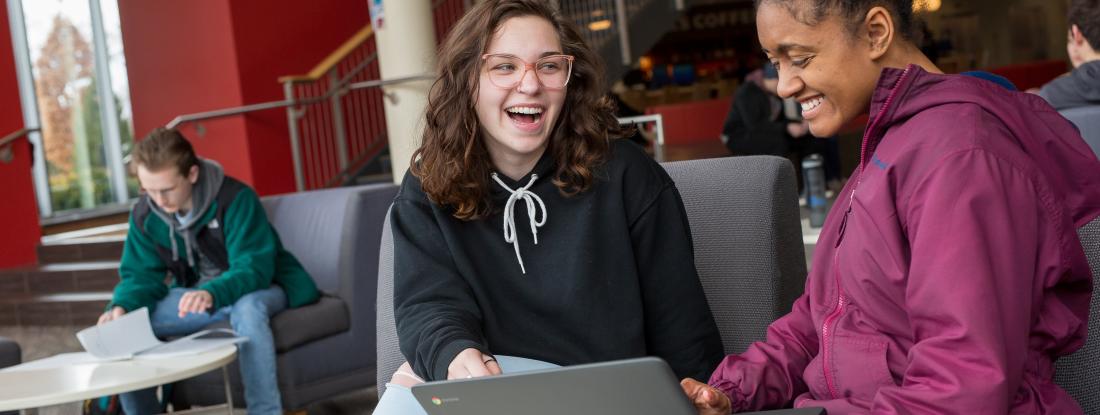 Two transfer students on Anderson Center talking with each other looking at a computer