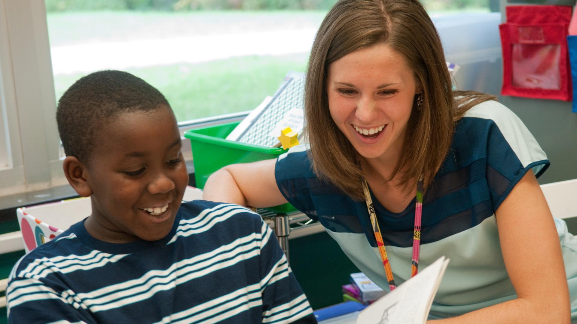Teacher (Alumni from Hamline's Education program) with student, reading a book