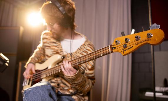 Student playing guitar in music production studio
